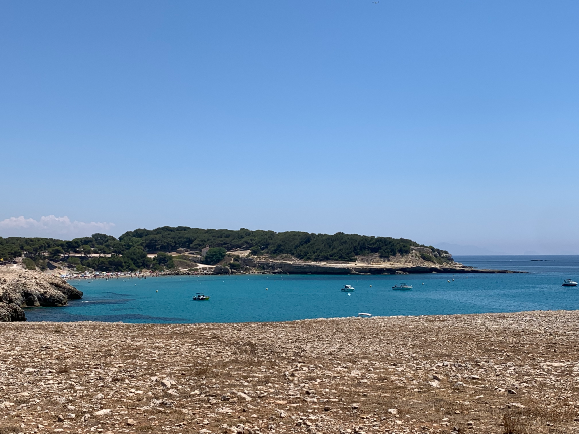 Martigues France, a view over the inlet with a stony shore and some bloats in a turquoise sea